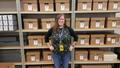 Primary view of [Amy San Antonio standing in front of archival boxes]