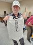 Photograph: [Steve Brooks holding up t-shirt of his design of Willie Nelson]