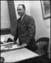 Photograph: [Dr. Ernest Clifton from the English Department near his desk]