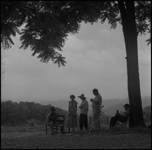 Primary view of object titled '[Photograph of a group talking under a tree, 1]'.