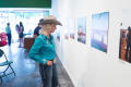 Photograph: [Cowgirl in Blue Examining Exhibit Photographs]