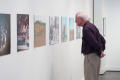 Photograph: [Man in Purple Shirt Examining Exhibit Photographs]