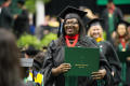 Photograph: [Graduate student holds diploma]