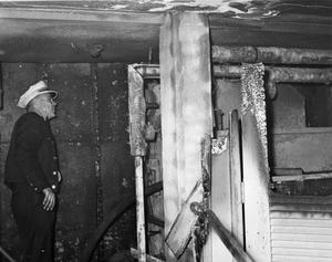 Primary view of object titled 'Aftermath of library fire, man Inspecting Fire Damage'.