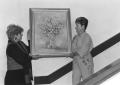 Photograph: President, Vivian Blevins hangs a painting by Shirley Koenig