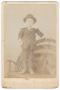 Thumbnail image of item number 1 in: '[Young Boy in Dark Clothing and Hat Standing on a Bench]'.