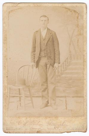 Primary view of object titled '[Unknown Young Man Standing Next to Wooden Chair]'.