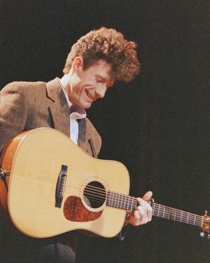 Primary view of object titled '[Lyle Lovett Holding a Guitar and Smiling]'.