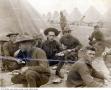 Photograph: [Group of World War I Army enlisted men eating beside tent rows]