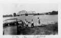 Photograph: [Four people standing near the banks of the flooded Brazos River.]