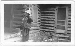Primary view of object titled '[Helen Moore holding a stringer of fish in front of a cabin]'.