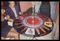 Primary view of [Six People Around a Circular Table With African Art]