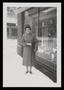 Primary view of [Sheila Emery Allen standing in snow next to storefront window]