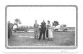 Photograph: [Three People Standing in a Field with Cars]