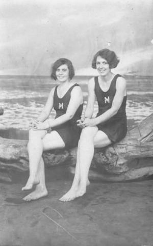 Primary view of object titled '[Two young women with bob haircuts sitting on a driftwood log]'.