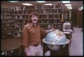 Photograph: [Man Stands by Globe in a Library]