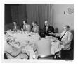 Photograph: [Lamar Fleming Jr. seated at formal breakfast with unidentified men]