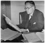 Primary view of [George A. Hill, Jr. sitting at desk reading book]