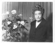 Primary view of [Miss Ima Hogg standing beside floral arrangement]