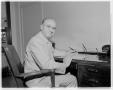 Photograph: [Man sitting at a desk at the Brooks Building]