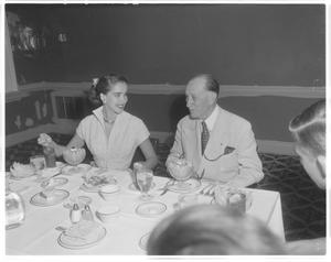 Primary view of object titled '[Julie Adams and man eating at table]'.