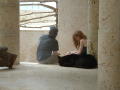 Photograph: [Young couple sit inside a stone structure, near a window]
