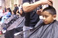 Photograph: [Students have their hair cut during a back to school fair]