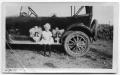 Photograph: [Young Girl Sitting on the Foot Step of an Automobile]