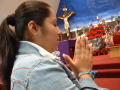 Photograph: [Woman prays in a church at Christmas time]