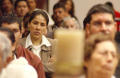 Photograph: [Woman listens to the priest along with the rest of the congregation]