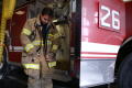 Photograph: [A fireman zips up his fire-fighting gear beside engine #26]