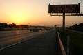 Photograph: [The sun sets over a highway with an Amber Alert sign]