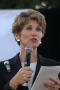 Photograph: [Laura Miller speaking into microphone with white paper in left hand]