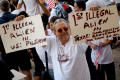 Photograph: [Jose Angel Gutierrez standing in crowd holding two handwritten signs]