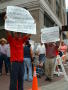 Primary view of [Two men hold up hand made signs in Spanish]
