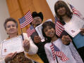 Photograph: [New United States citizens hold up their certifactes and U. S. flags]