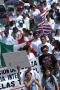 Photograph: [Marchers carry signs and the flags of the United States and Mexico]