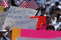 Photograph: [Signs are raised by protesters]