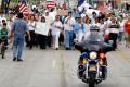 Photograph: [Group of Protesters Walking Behind Police Officer on Motorcycle]