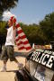 Photograph: [Man with a U.S. flag walks past a police car]