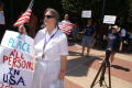 Photograph: [Several anti-immigration protesters with signs and U.S. flags]