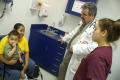 Photograph: [Dr. Henry Lenk and clinic staff member look at mother and child]