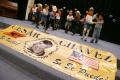 Photograph: [Group of young dancers perform behind banner for Cesar Chavez Day]