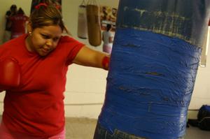 Primary view of object titled '[Girl in red shirt hitting heavy bag]'.