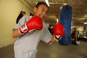 Primary view of object titled '[Boy in red boxing gloves in front of blue heavy bag]'.