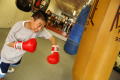 Photograph: [Boy in red boxing gloves hitting heavy bag]