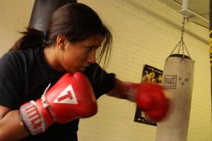 Primary view of object titled '[Young woman in red boxing gloves hitting heavy bag]'.
