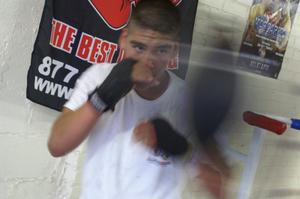 Primary view of object titled '[Young man wearing hand wraps hitting boxing bag]'.