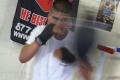 Photograph: [Young man wearing hand wraps hitting boxing bag]