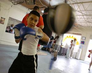 Primary view of object titled '[Young boy in boxing gloves hitting speed bag]'.